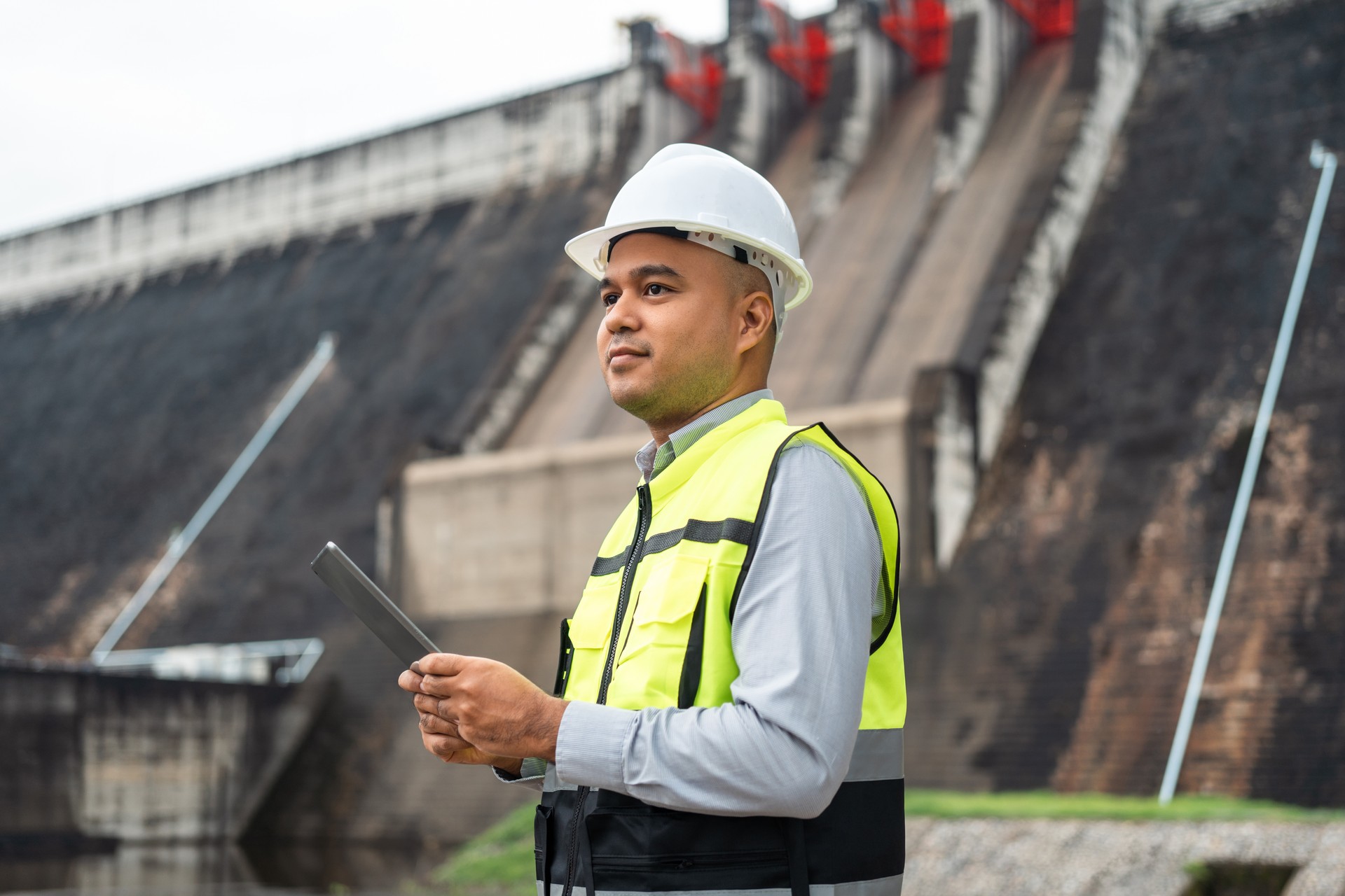 Ingeniero de mantenimiento asiático profesional con casco de seguridad en la construcción de la presa de la obra con la central hidroeléctrica y el riego. Ingeniero gerente que trabaja en el proyecto de gran edificio.