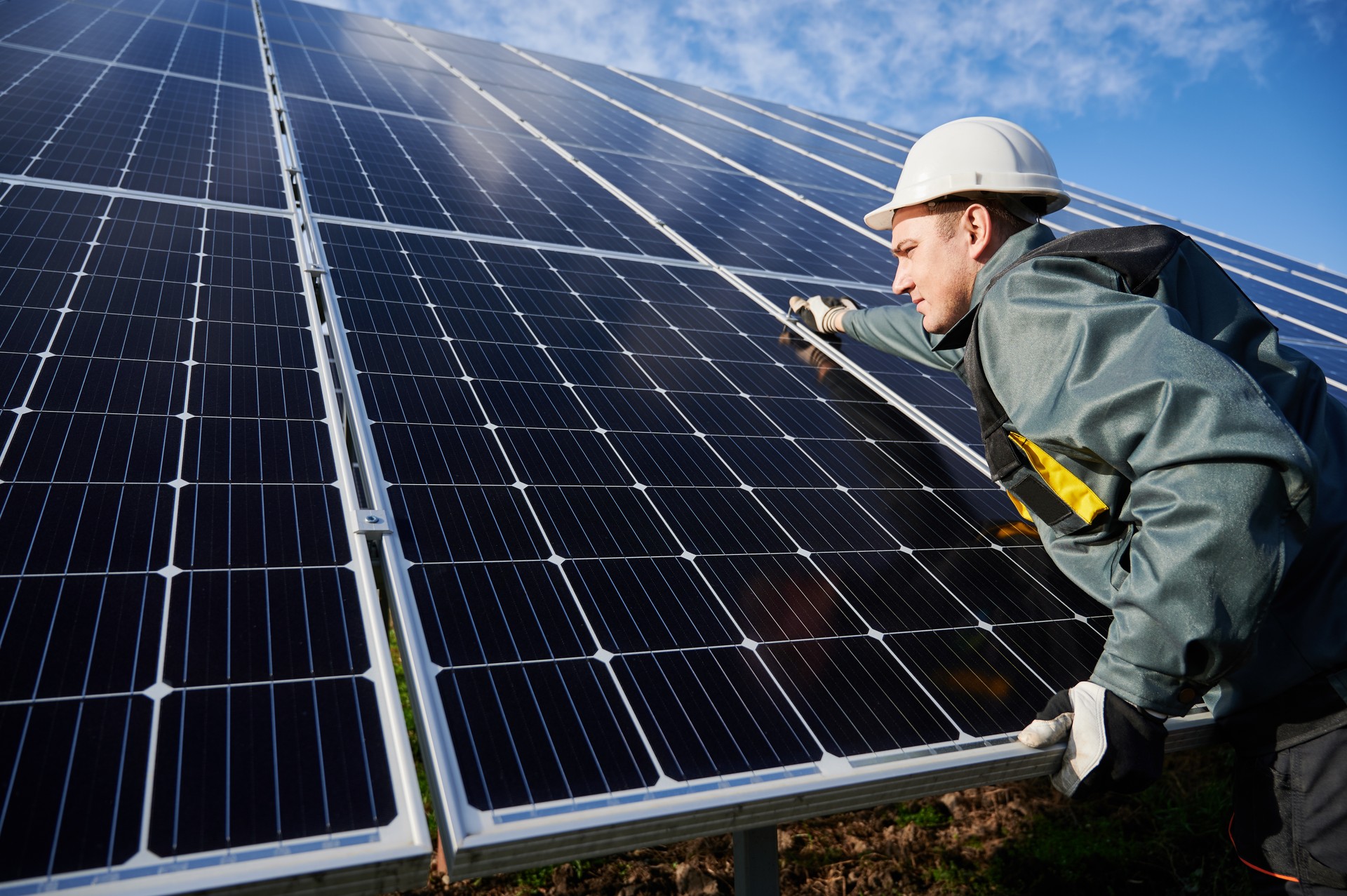 Obrero de pie en el suelo tratando de sujetar las baterías solares juntas, instalando el proceso