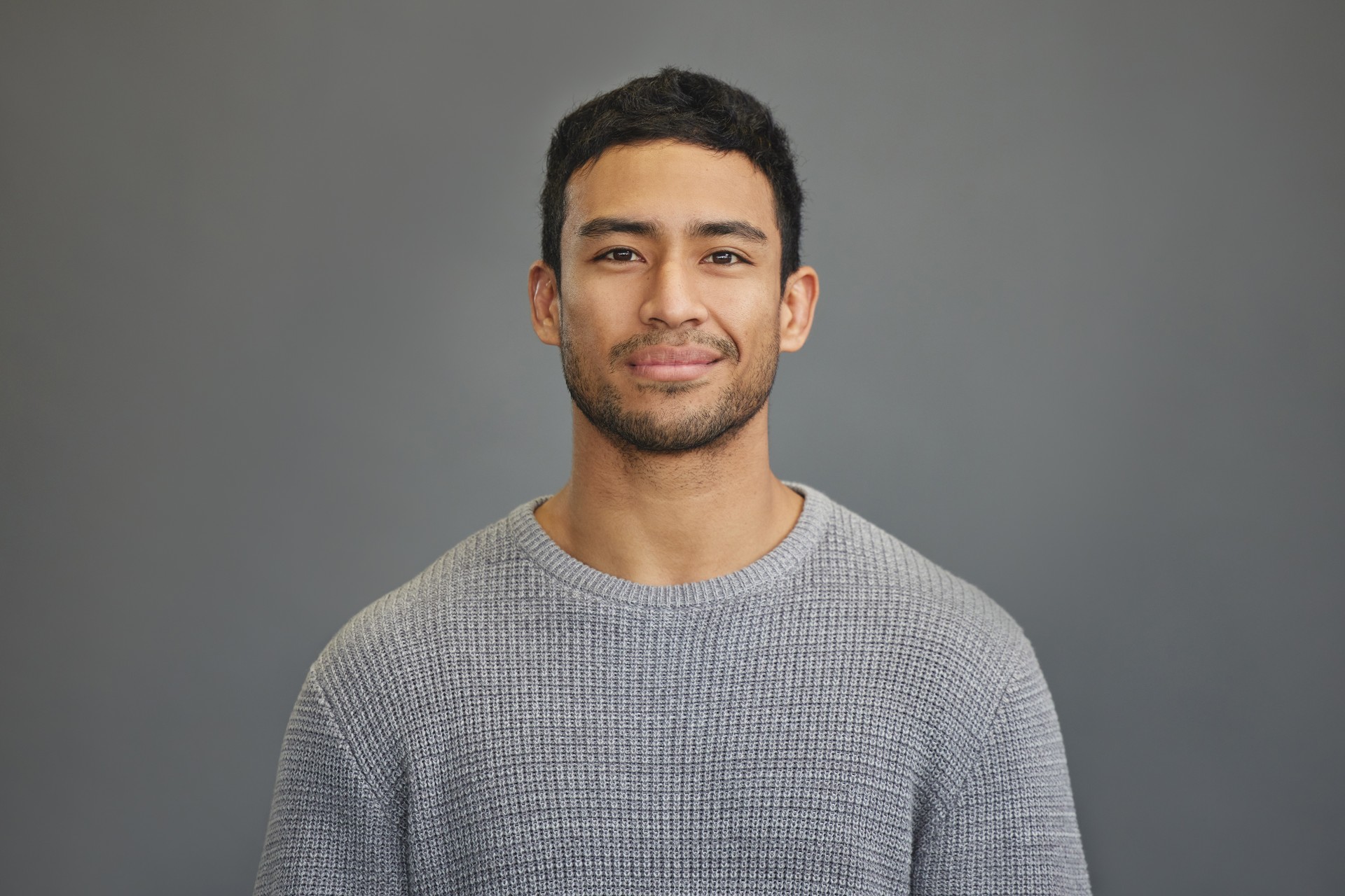 Foto de un joven guapo de pie sobre un fondo gris